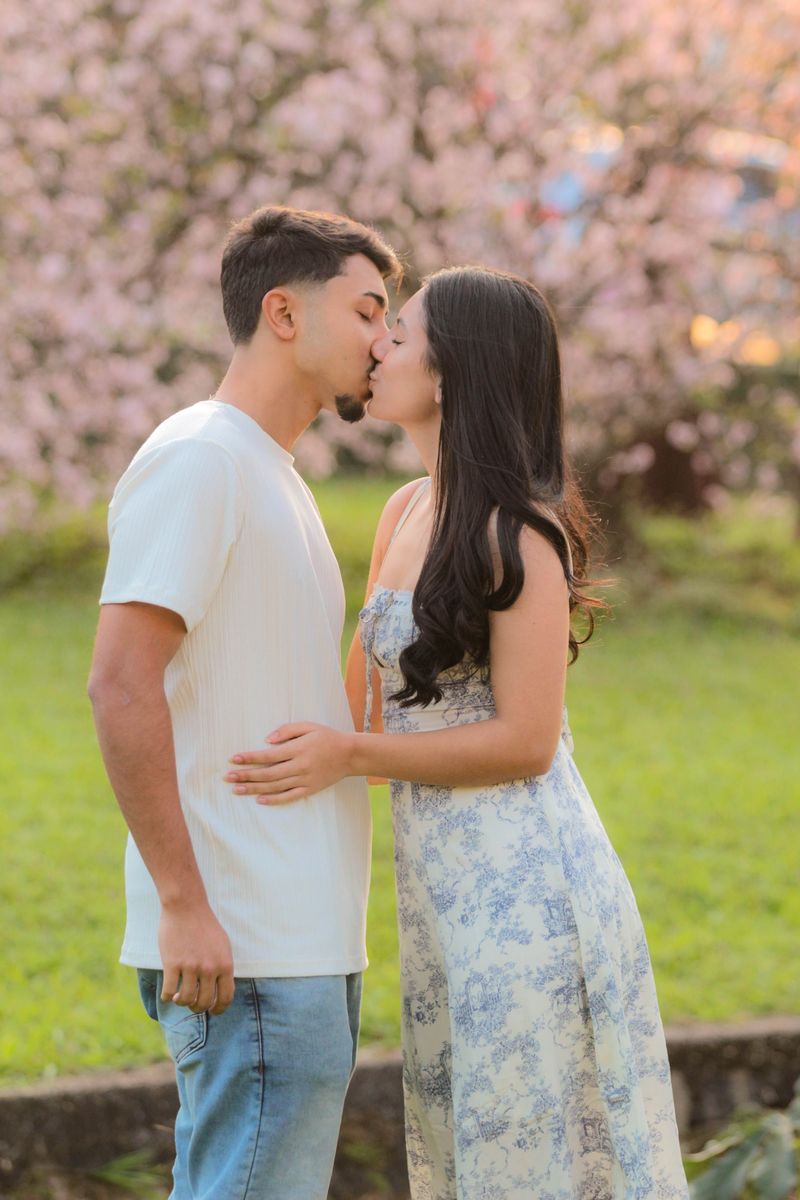 Casal se beijando sob árvore florida