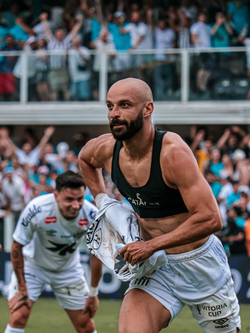 Disputa de bola durante partida com torcida ao fundo