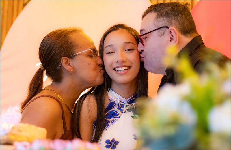 Pais beijando a filha durante festa de aniversário